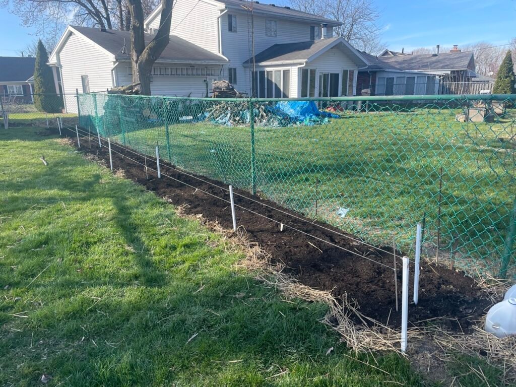 Soil prepped along a fence for a future garden.