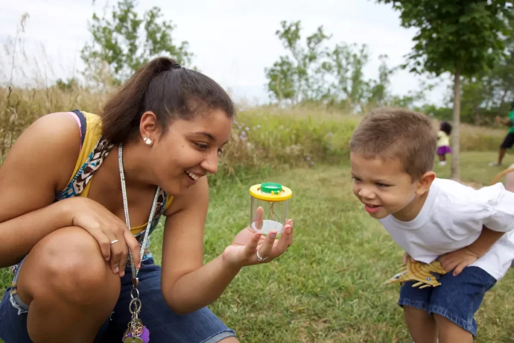 A girl showing a young boy an insect in a container.